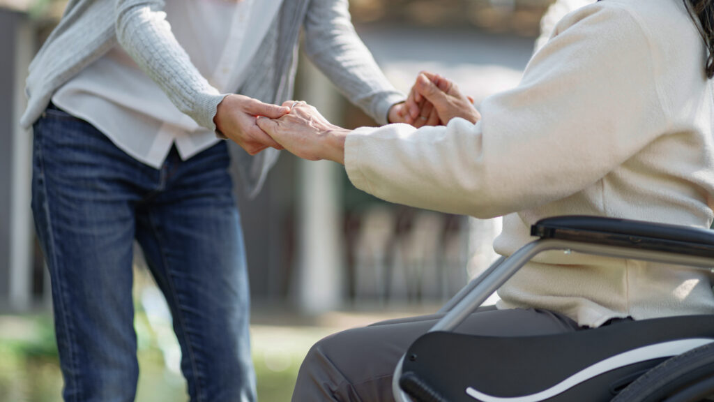 Nursing home, Young caregiver helping senior woman in wheelchair, Volunteer.